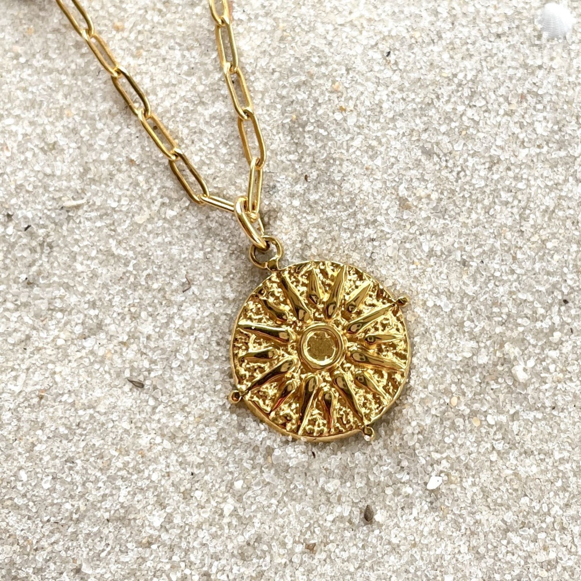 Journey gold necklace on sand closeup