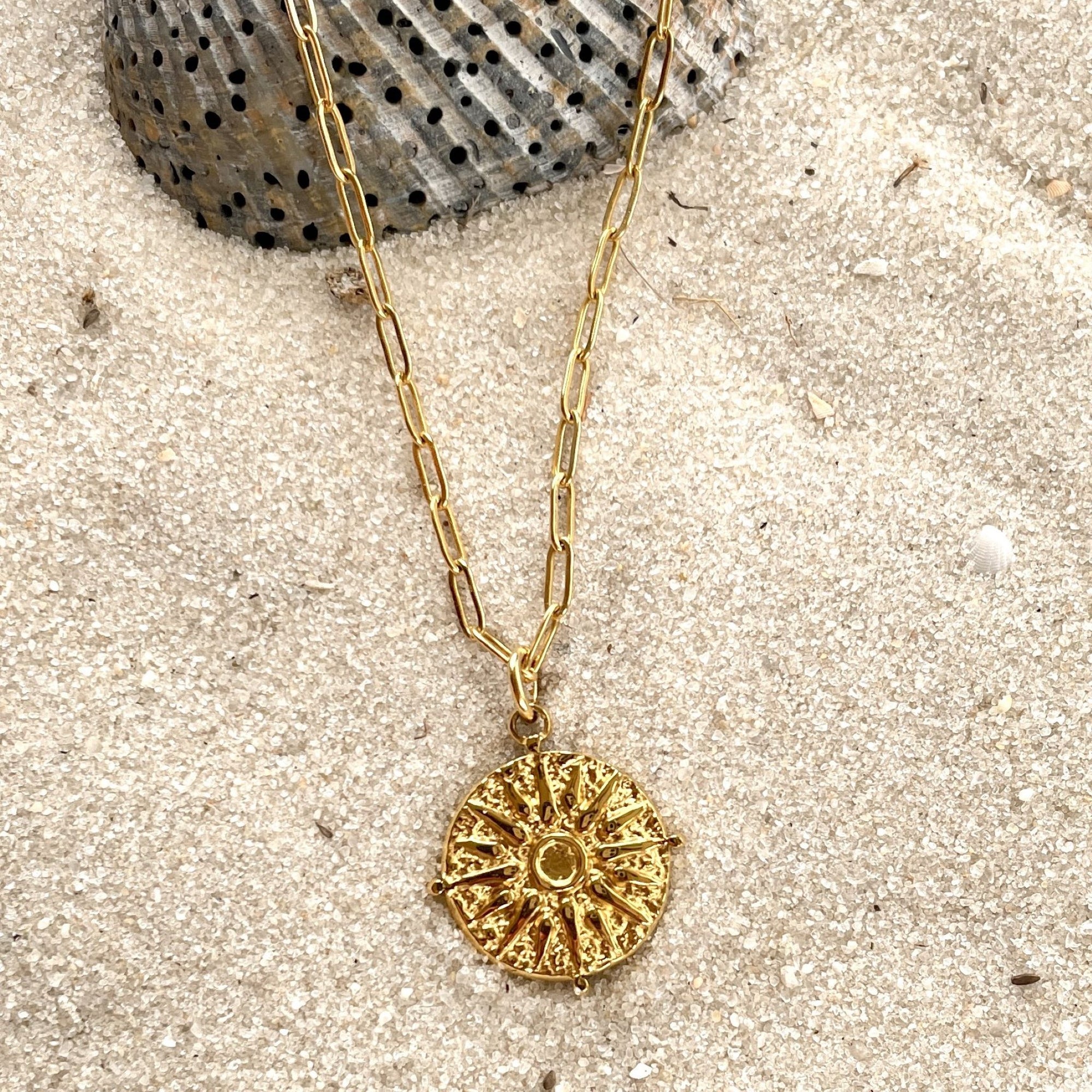 journey gold necklace on sand with shell