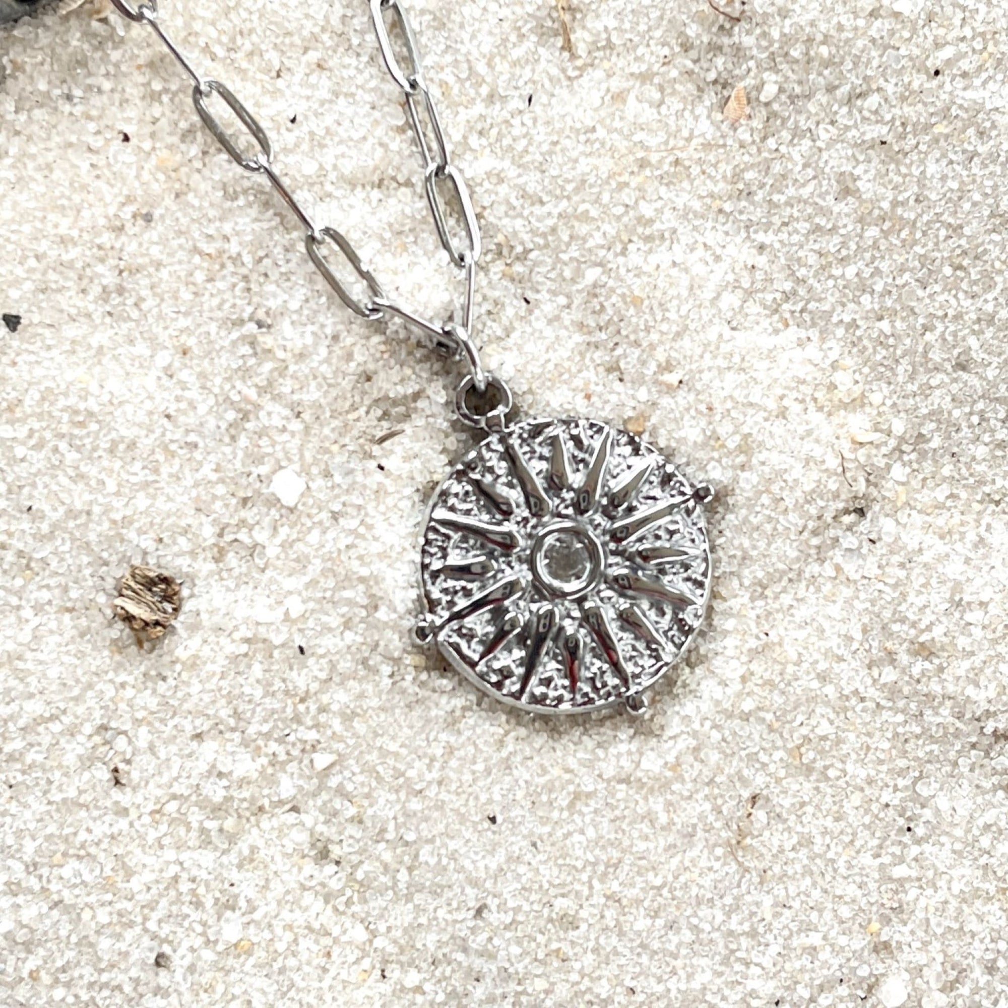 journey stainless steel silver necklace on sand background close up