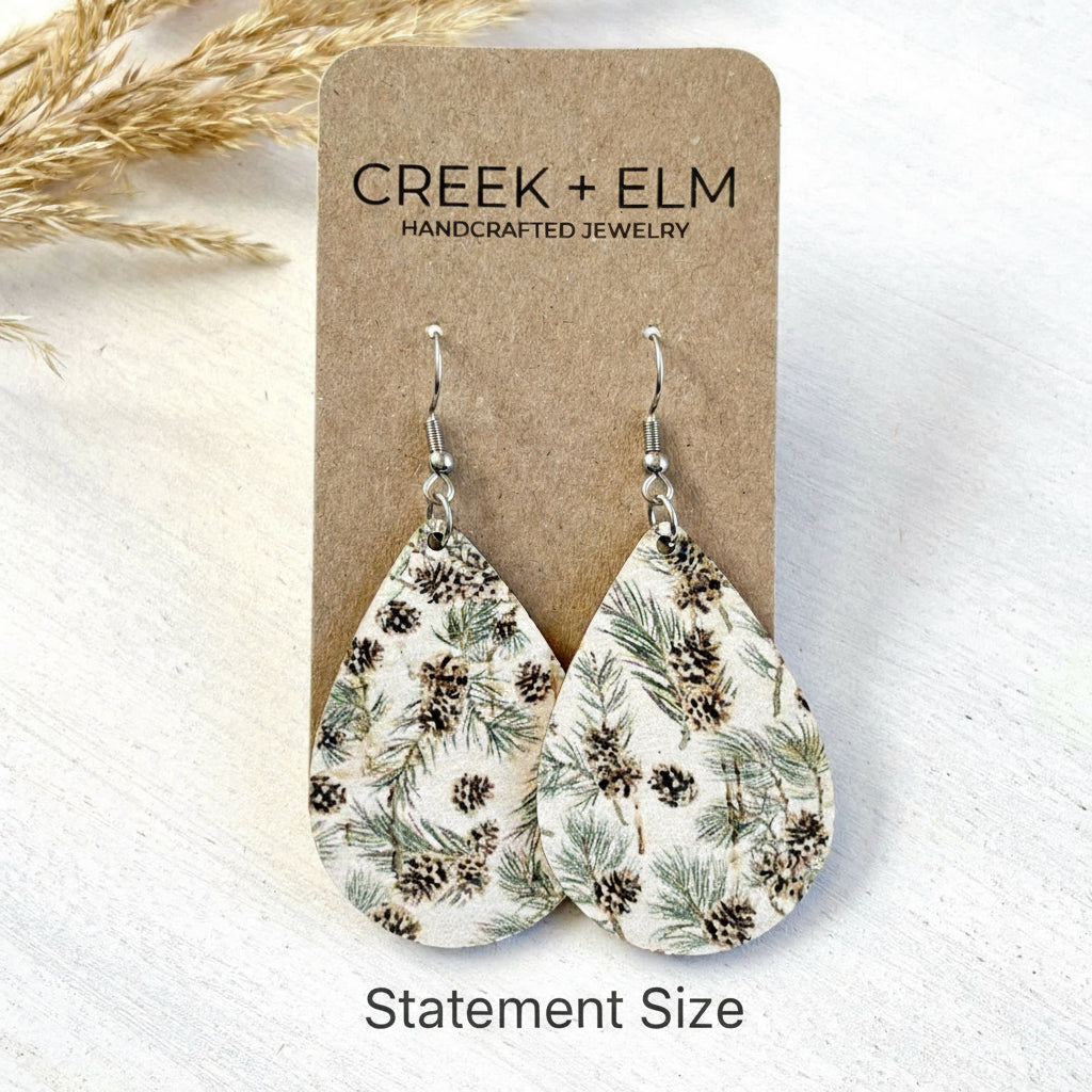 Teardrop-shaped earrings with nature design on a Creek + Elm branded card.