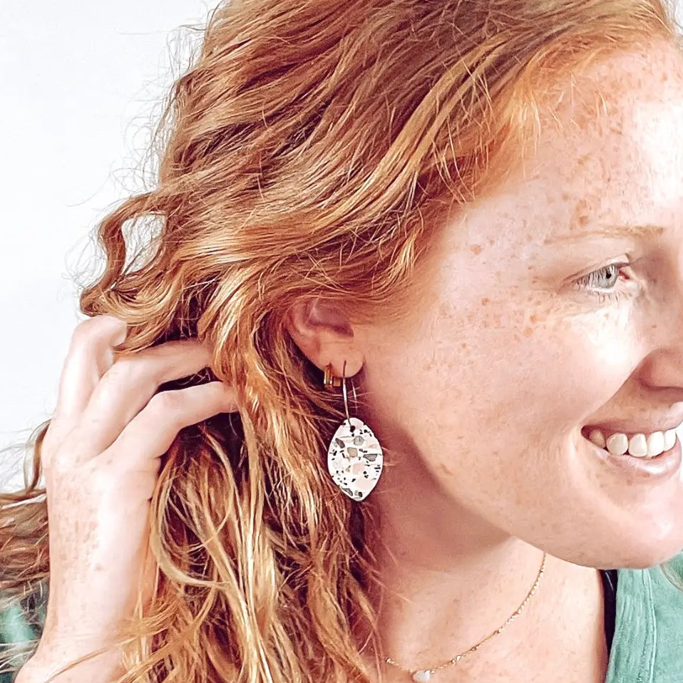 Woman showcasing the Terrazzo cork leaf hoop dangle earrings 