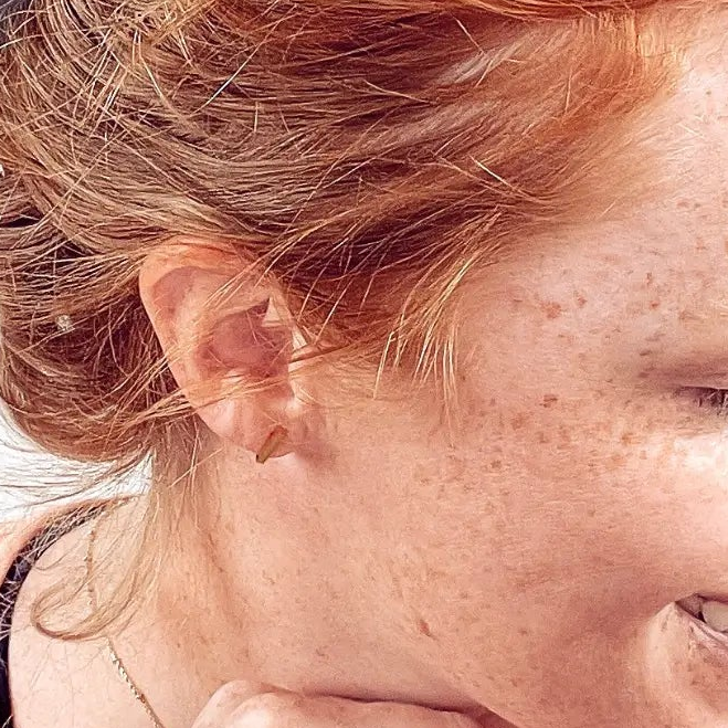Close up of the Gold stainless steel bar stud earrings worn on one ear 