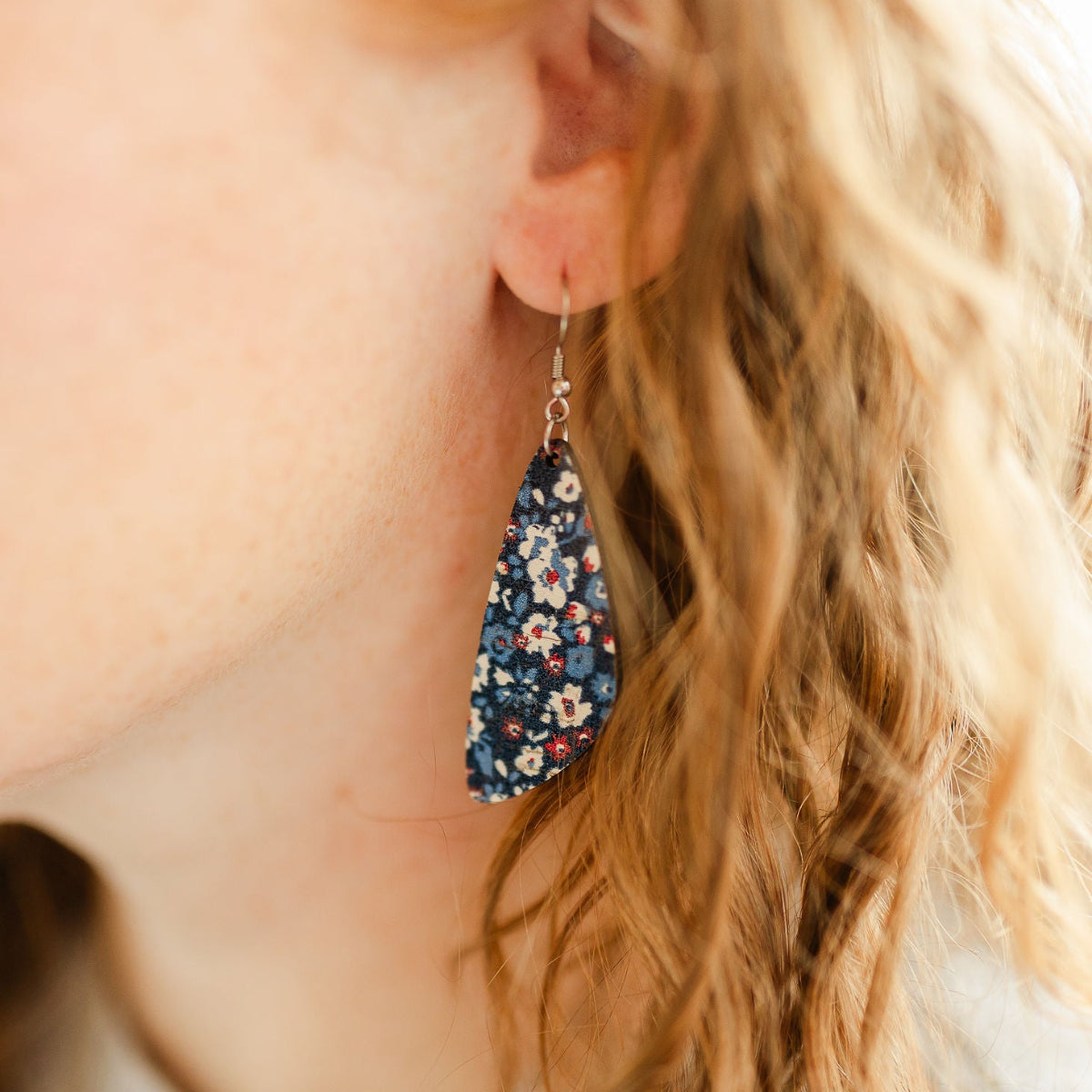 Close up of the Eliza Patriotic Poppies cork teardrop earrings worn on one ear