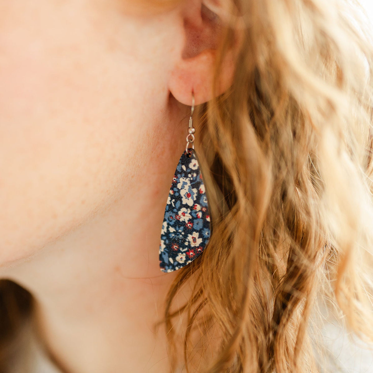 close up on ear shot of eliza patriotic poppy cork teardrop earrings