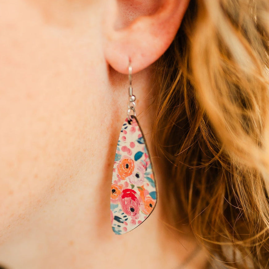 Close up of the Eliza Summer Garden cork teardrop earrings worn on one ear