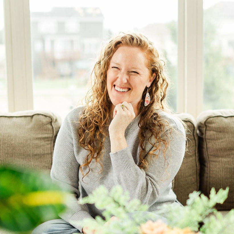 Woman on couch showcasing the Eliza Summer Garden cork teardrop earrings 