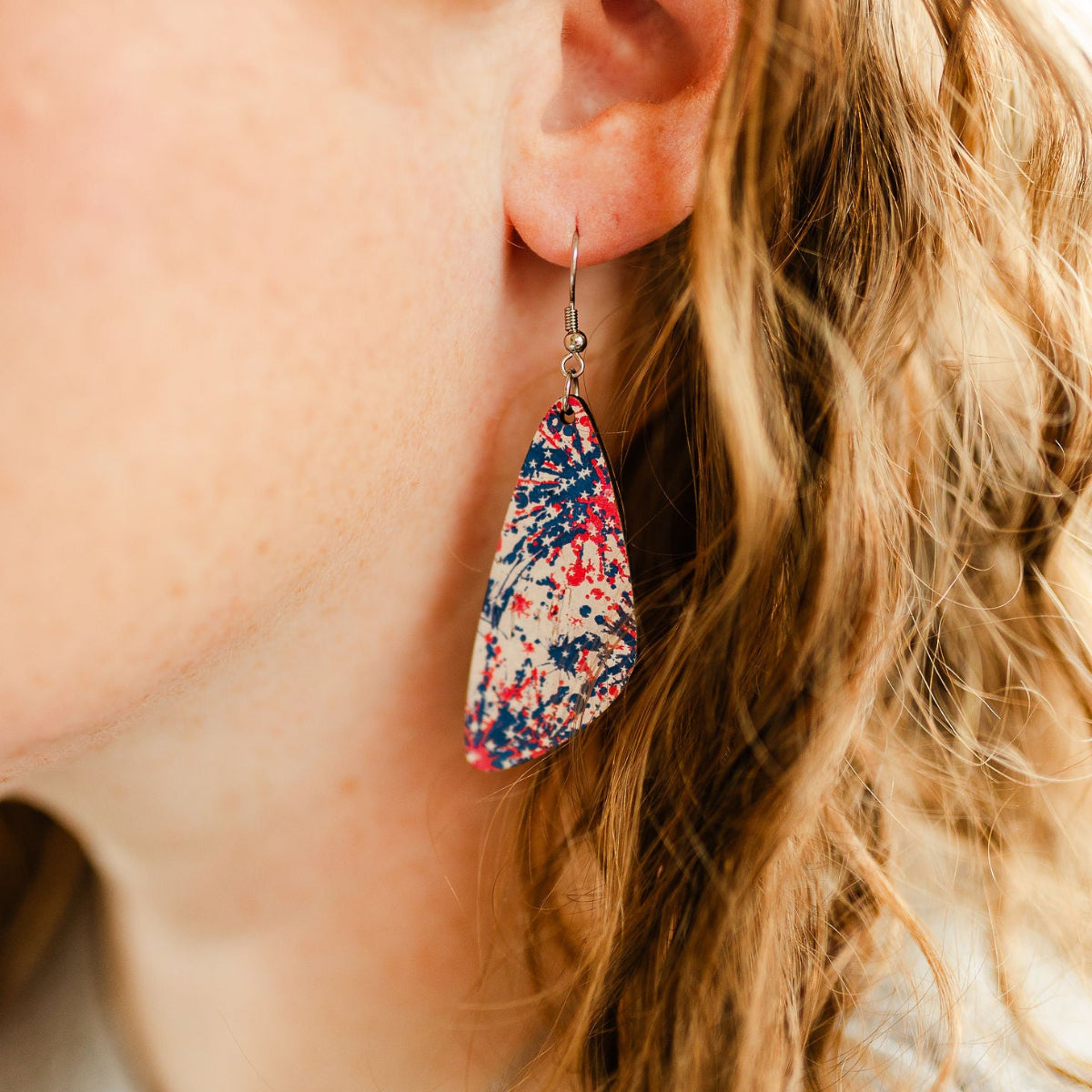 Close up shot of the Eliza Star Spangled cork teardrop earrings worn on one ear