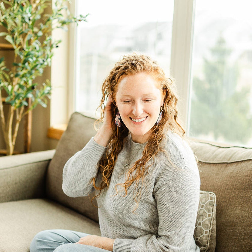Woman on couch wearing the Eliza Star Spangled cork teardrop earrings 