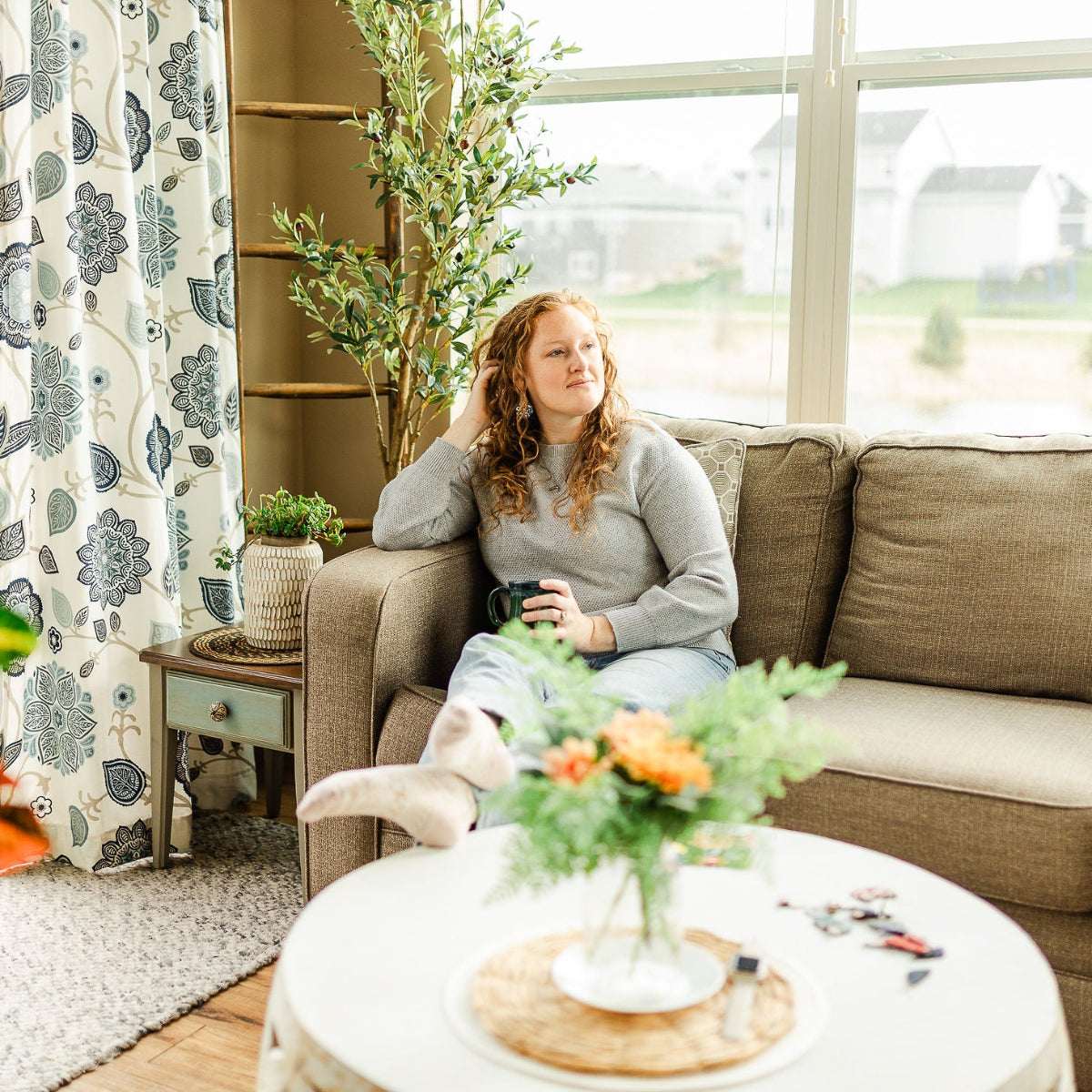 Woman sitting on a couch while holding a cup