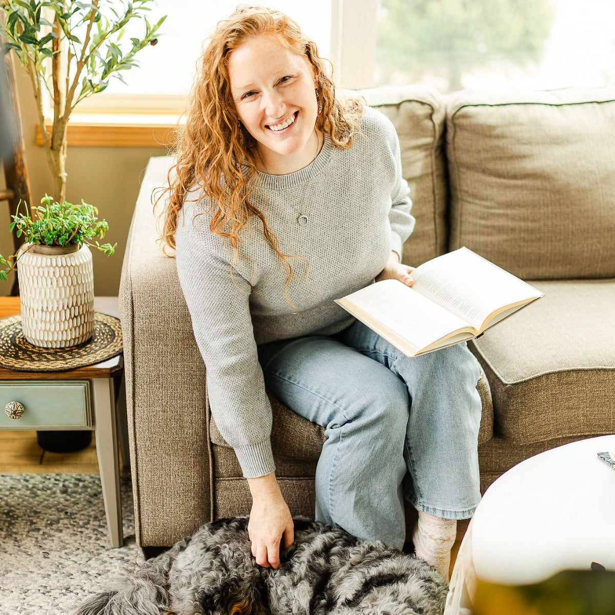 Woman holding a book while playing with her dog
