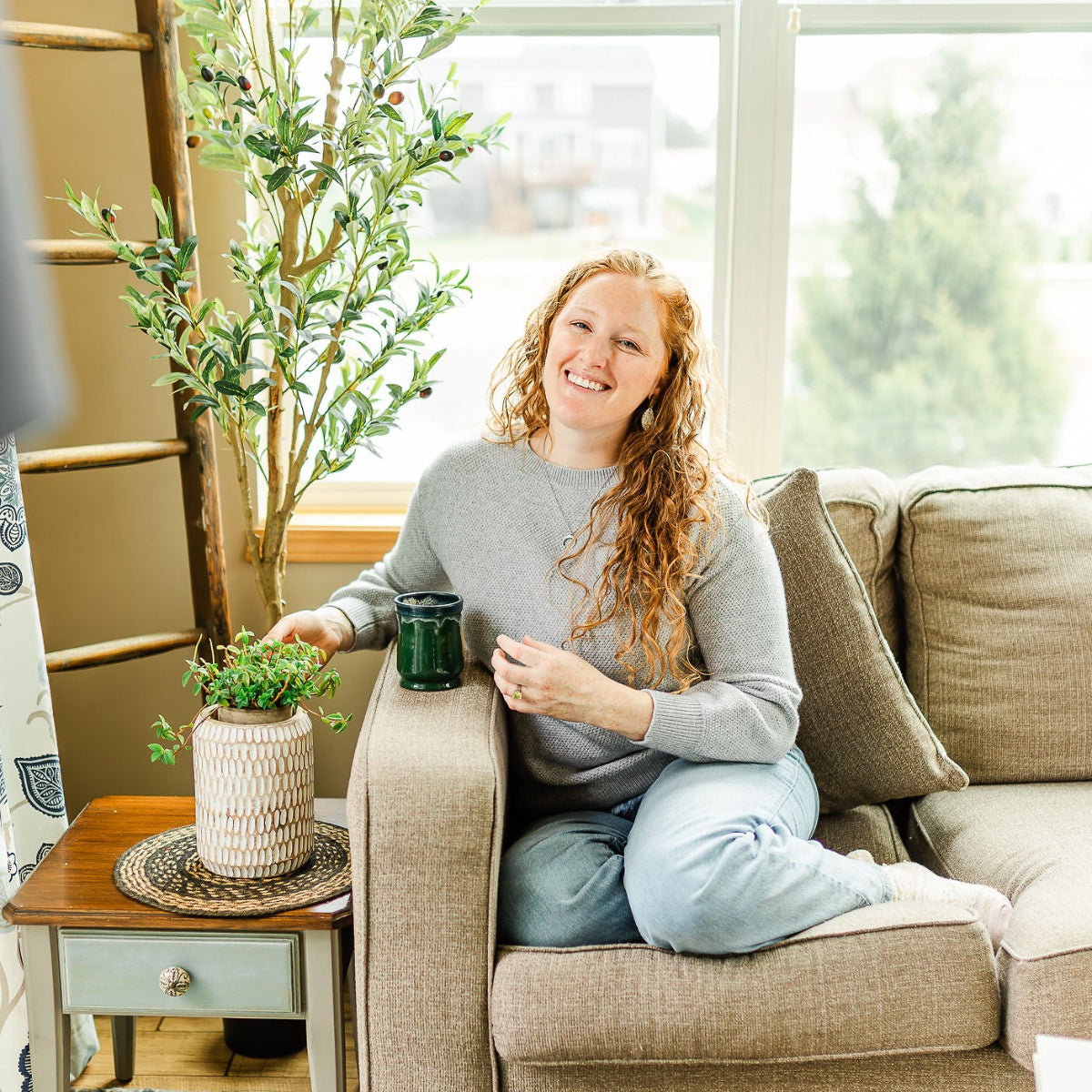 Woman on couch showcasing the Wildflower cork and walnut leaf earrings