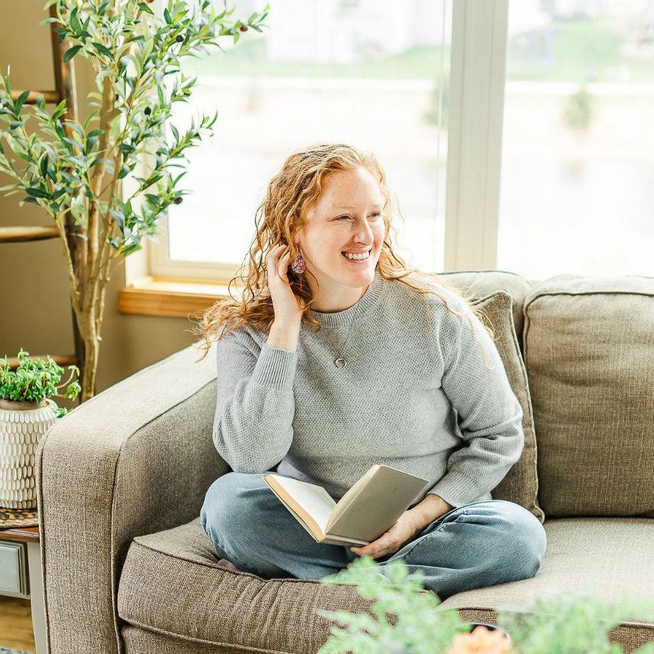Woman holding a book while wearing the mini Kendra star spangled cork teardrop earrings 