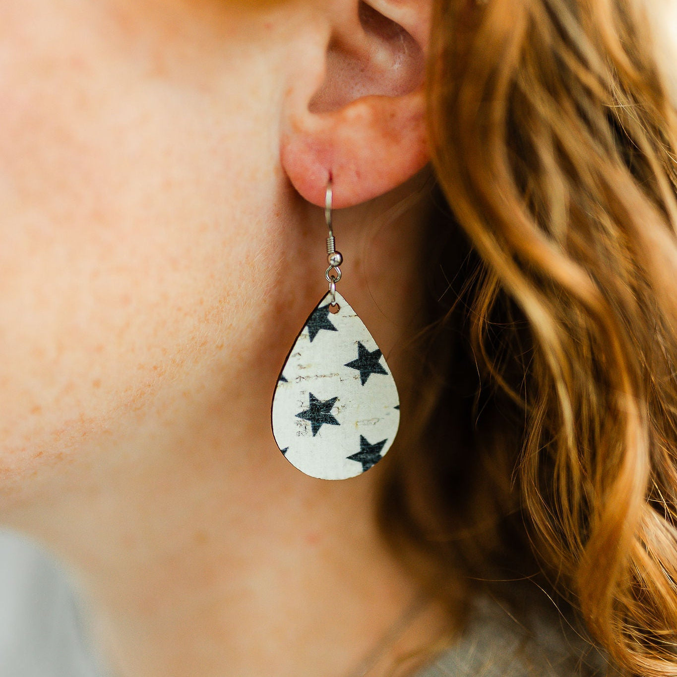 Close-up of a person wearing star-patterned teardrop earrings.