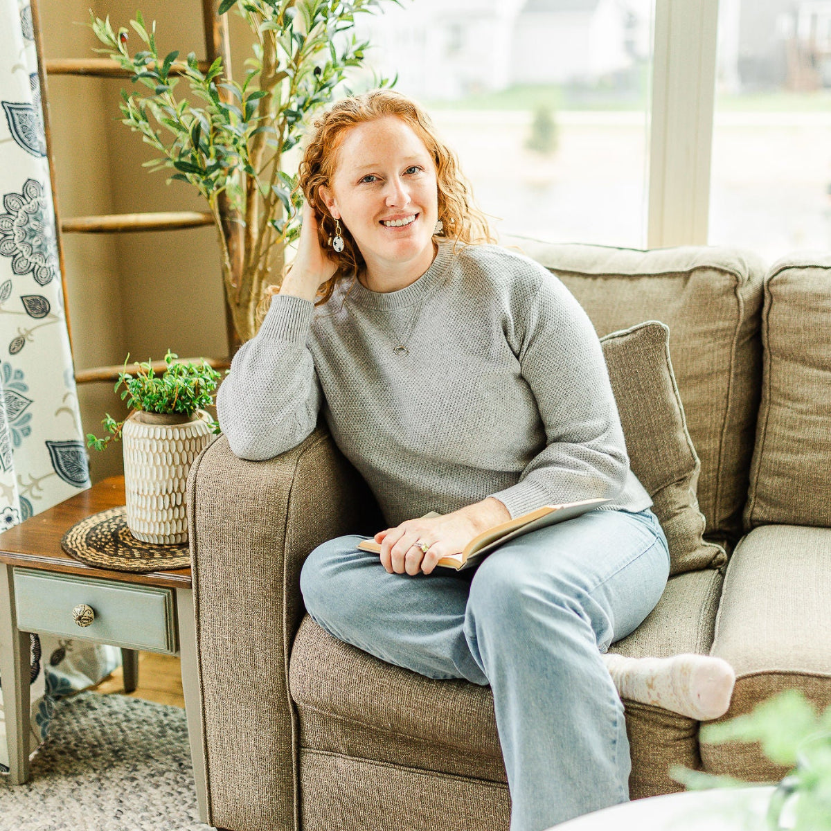 woman chilling on a couch while showcasing the Pair of Elizabeth blue stars cork hexagon earrings 