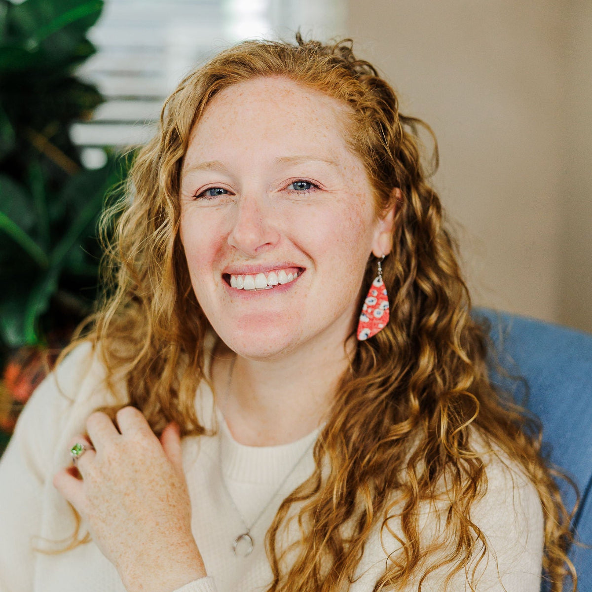 Woman smiling on camera while wearing a red vibrant earrings