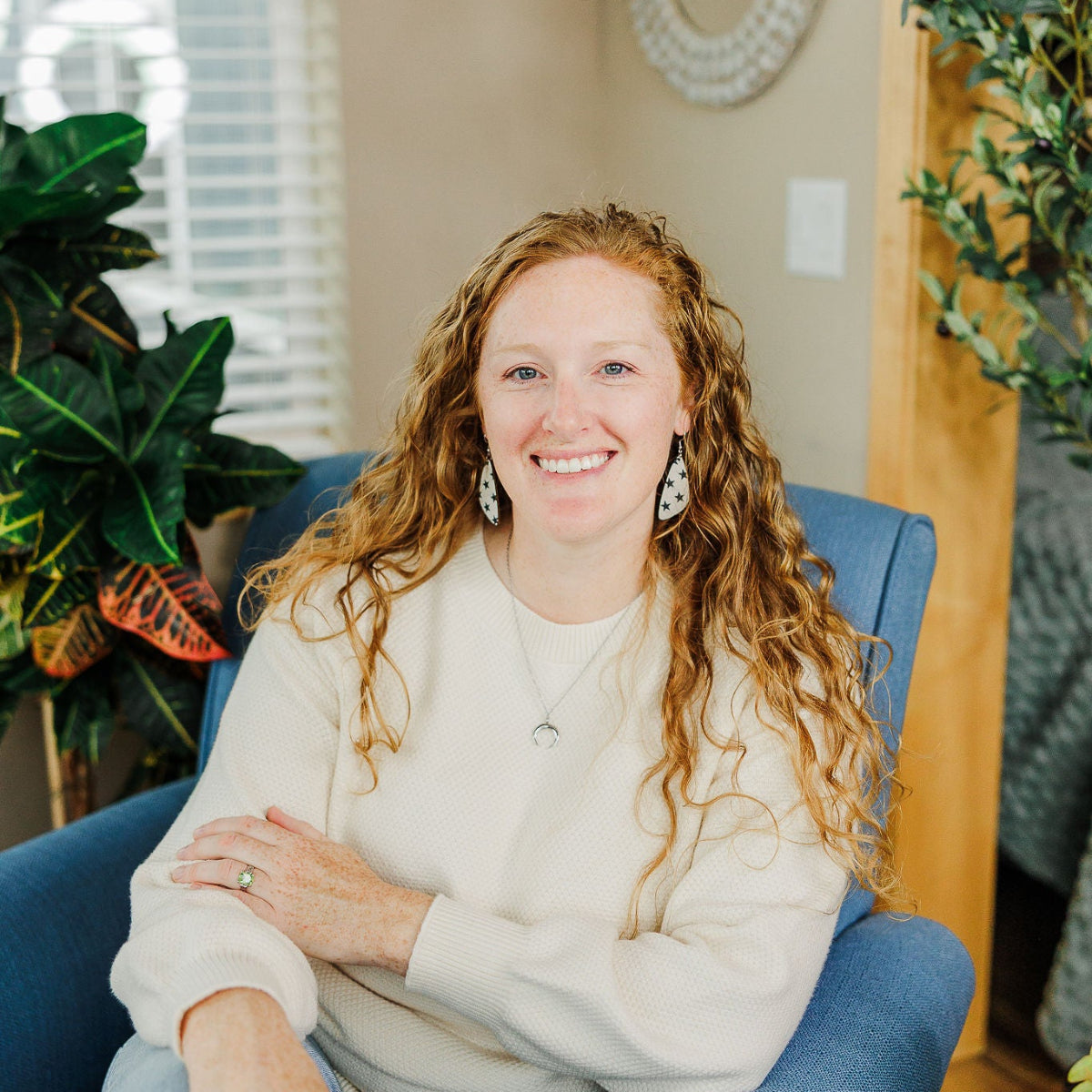 Woman sitting on couch while wearing a creek+elm earrings