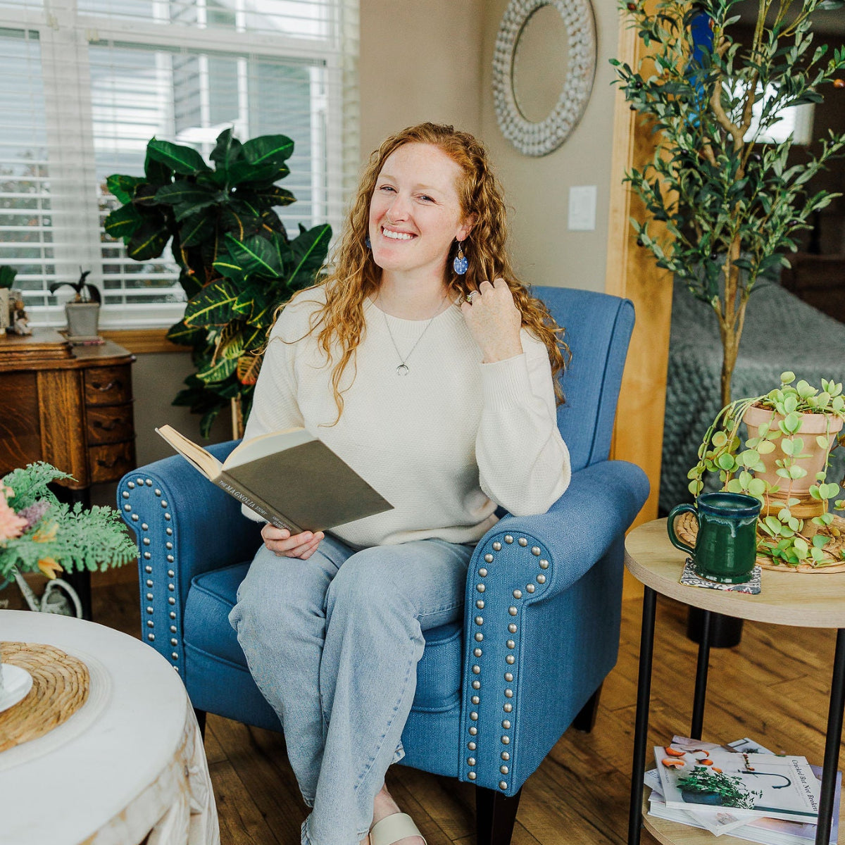 Woman sitting on a couch while showcasing the creek+elm earring