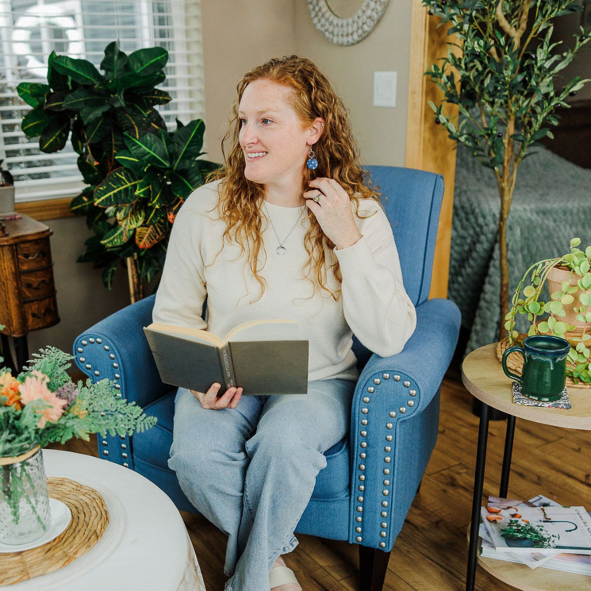 woman on couch holding a book and wearing the creek+elm earring