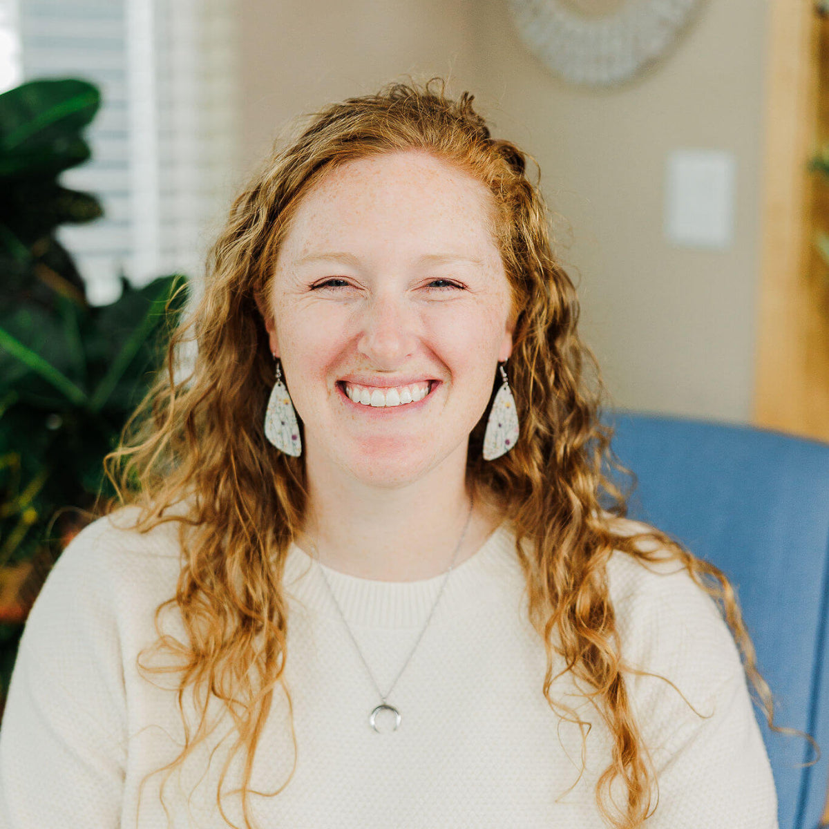 Woman smiling while showcasing the Creek+Elm earrings 