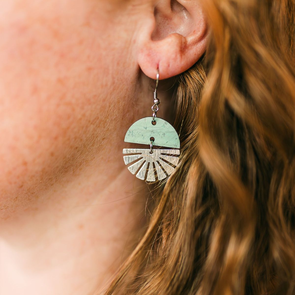 Seafoam green earrings with silver starburst accent and soft finish on packaging