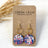 Gold Elizabeth star spangled cork and hexagon earrings on plain background