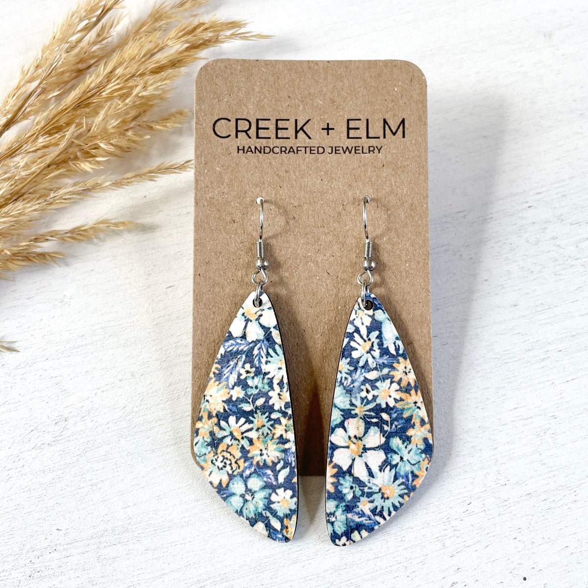 Front angle of the Eliza blue floral cork teardrop earrings on packaging 