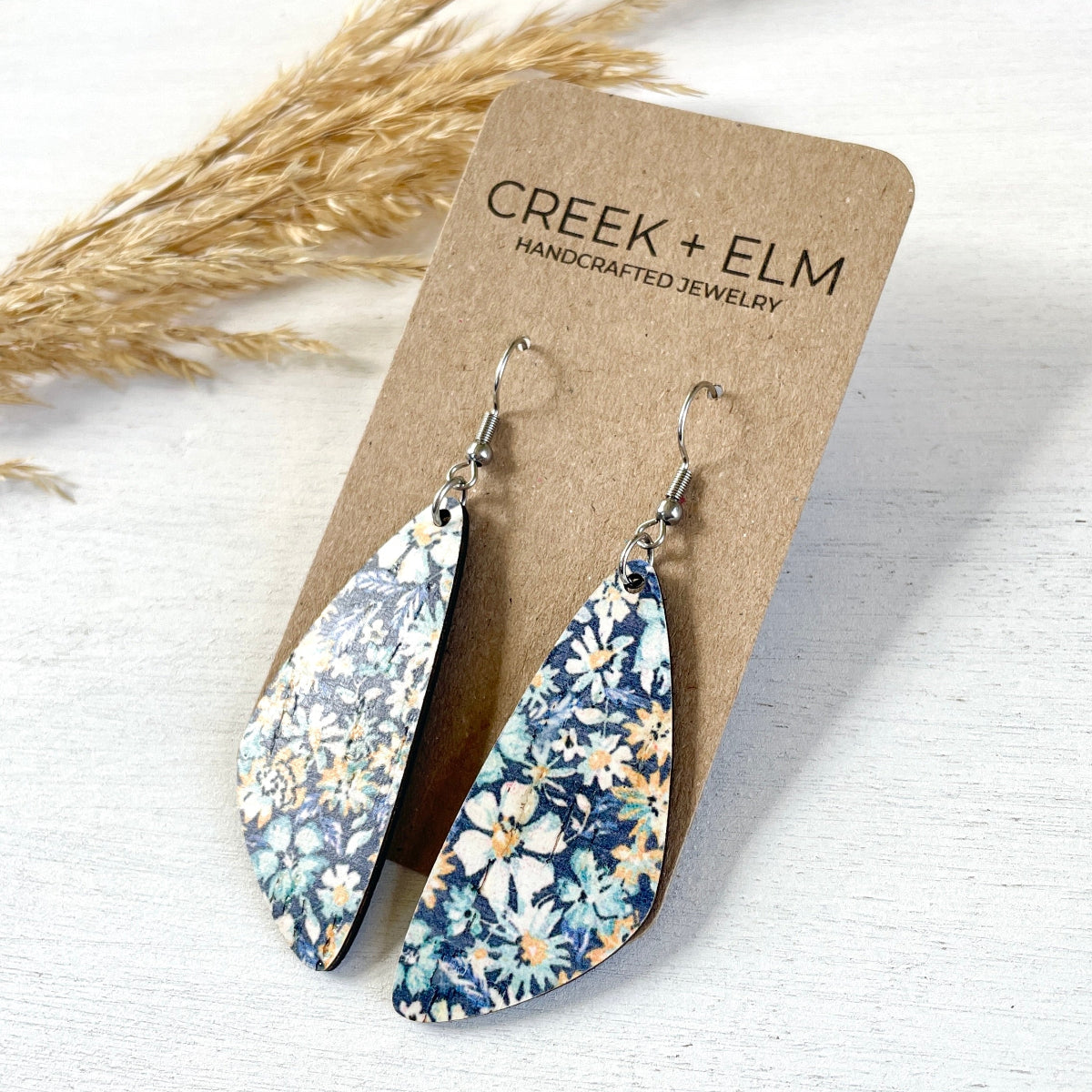 Side angle of the Eliza blue floral cork teardrop earrings on packaging 