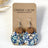 Close up on Packaging of the Cora Blue Floral cork and walnut earrings 
