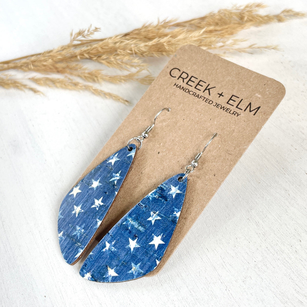 Side angle of the Eliza Denim Stars cork teardrop earrings on a plain background