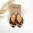 Creek+Elm 3 layer cork and vegan leather striped earrings on a packaging 