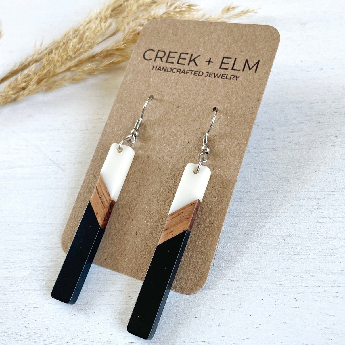 Carded photo of a creek and elm tri-color earring