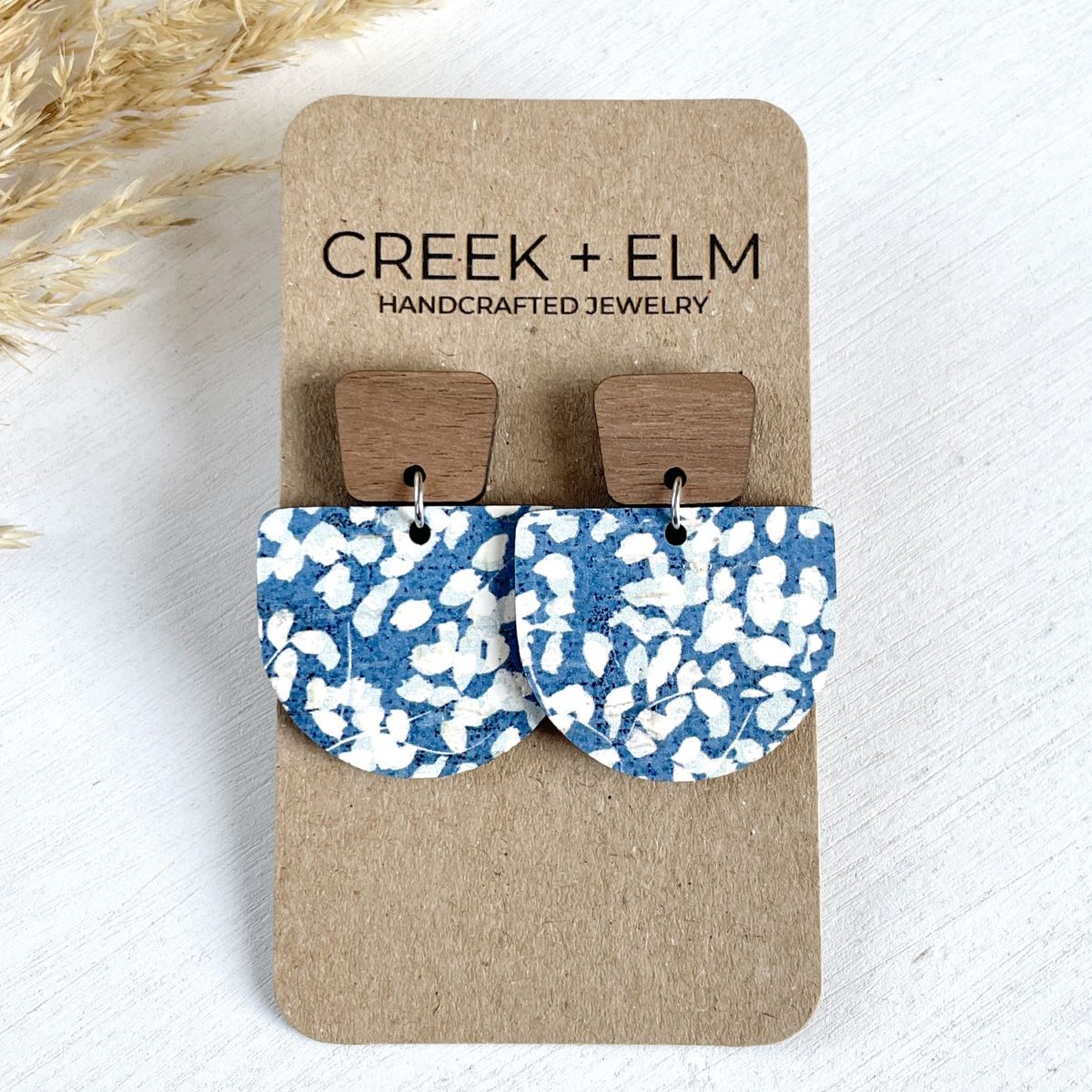 Blue dotted cork earrings with walnut trapezoid post and curved drop on packaging