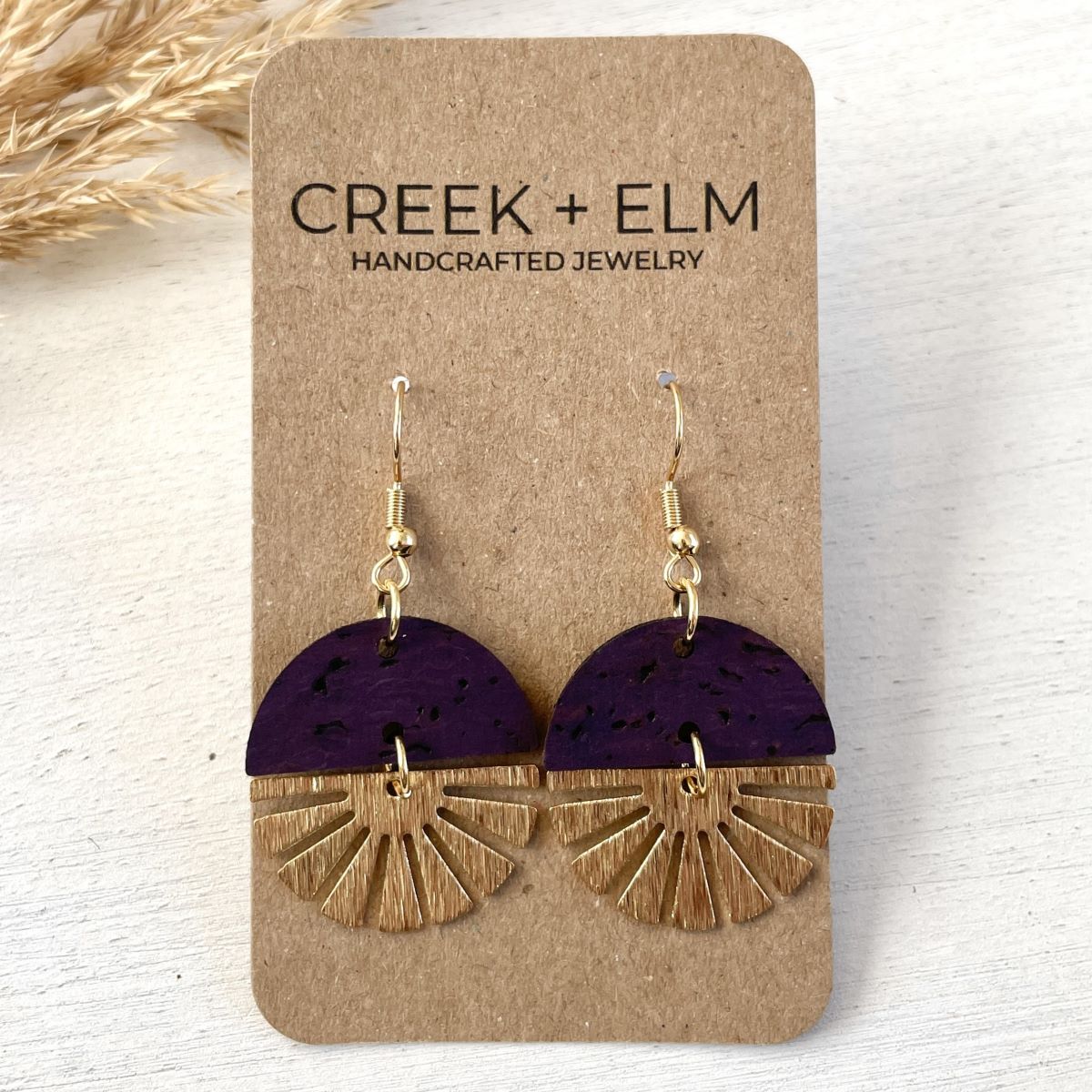 Eggplant earrings with gold starburst detail and deep tone on packaging