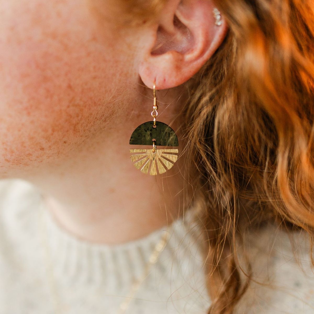 Olive earrings with gold starburst detail and earthy finish on packaging