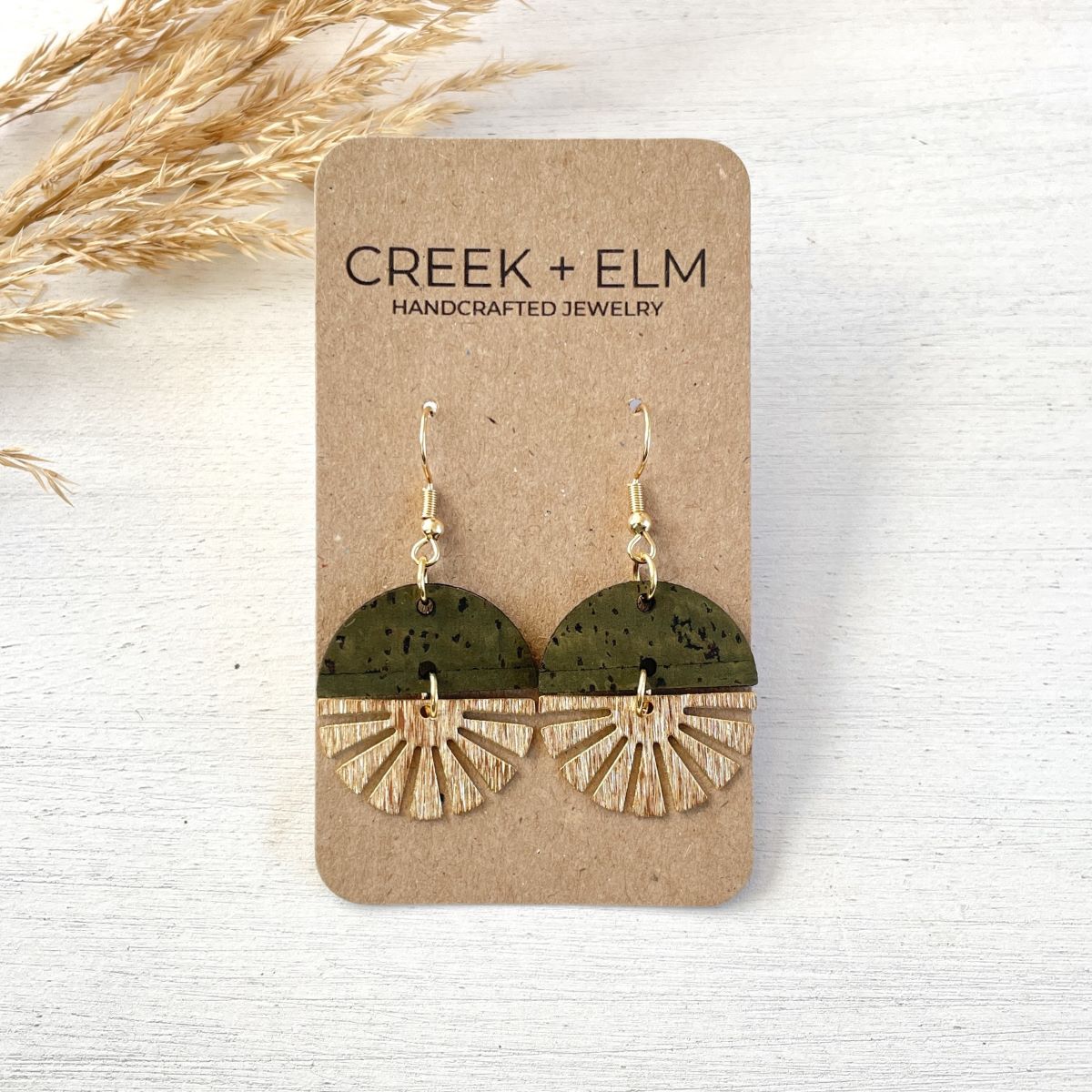 Olive earrings with gold starburst detail and earthy finish on packaging