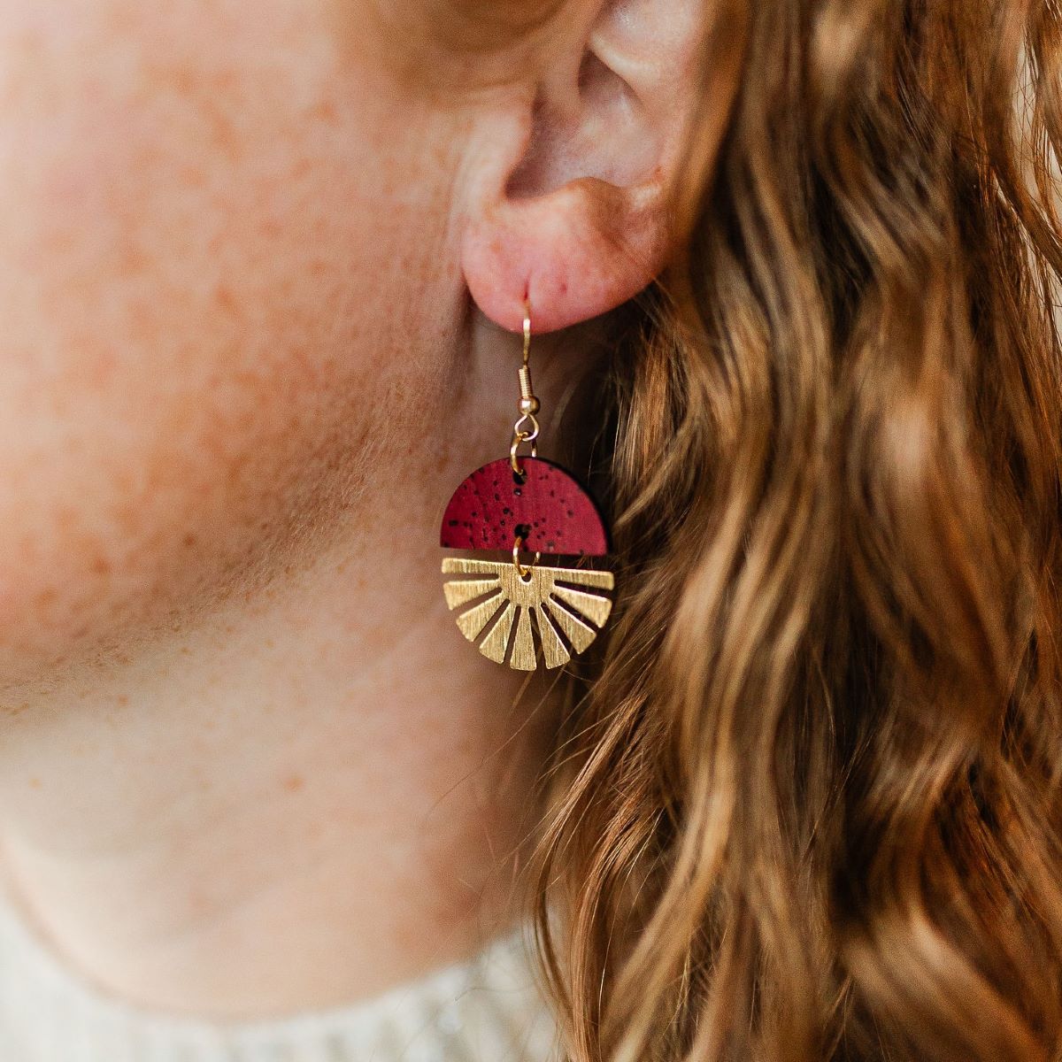 Red wine earrings with gold starburst detail and rich tone on packaging