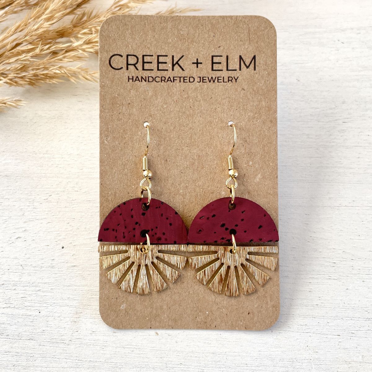 Red wine earrings with gold starburst detail and rich tone on packaging