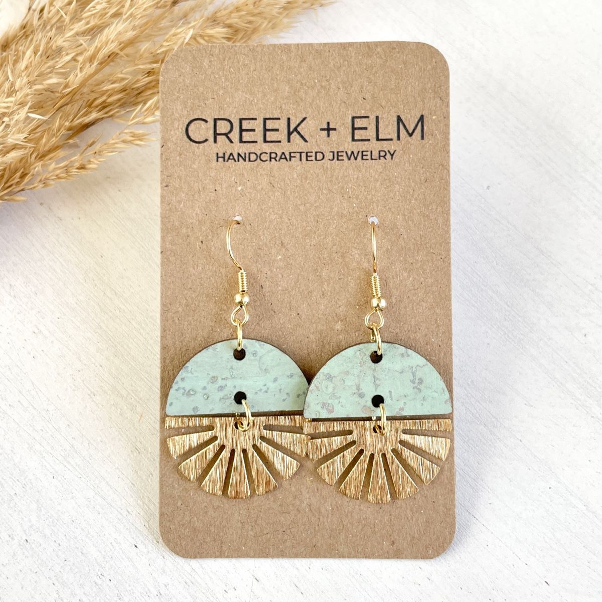 Seafoam earrings with gold starburst detail and soft tone on packaging 
