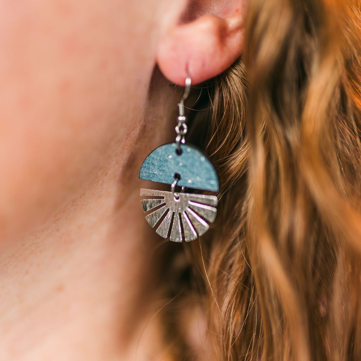 Pearl gray earrings with silver starburst detail in a soft neutral tone on packaging