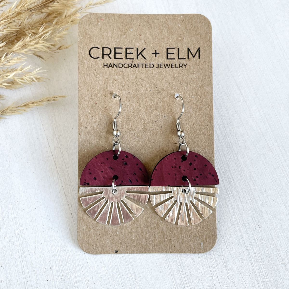 Deep red wine earrings with silver starburst detail and rich tone on packaging