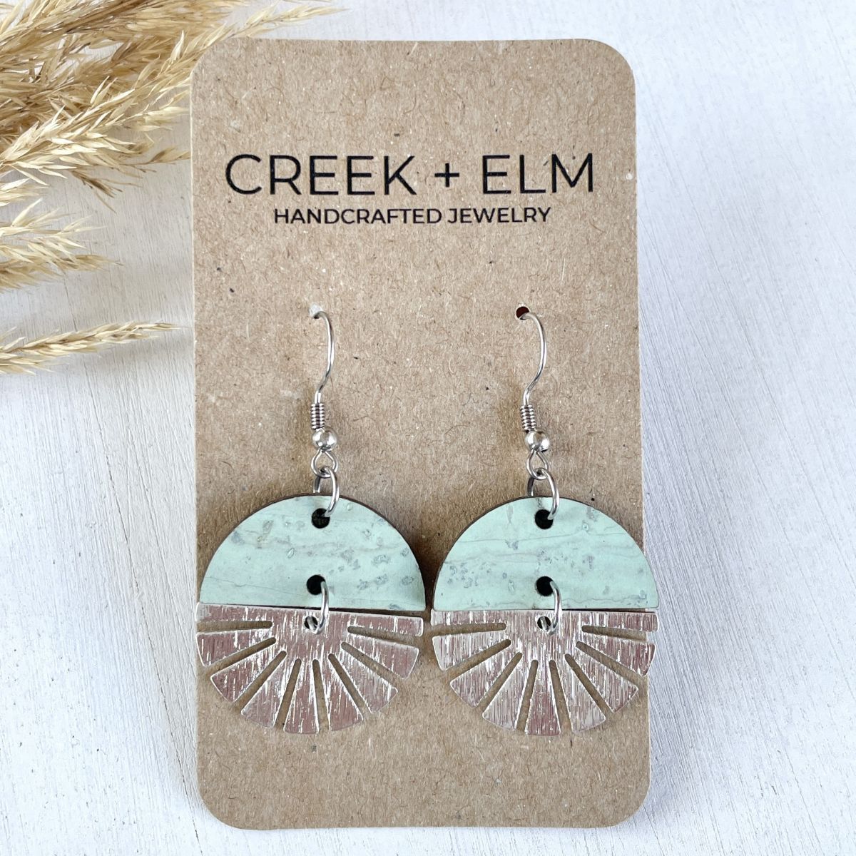 Seafoam green earrings with silver starburst accent and soft finish on packaging