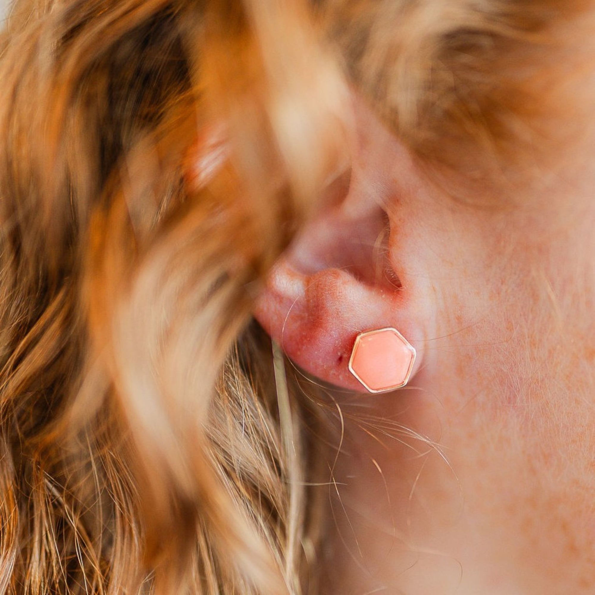 clay hexagon studs coral on ear closeup