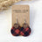red buffalo plaid cork cutouts nested into a walnut circle on a fish hook
