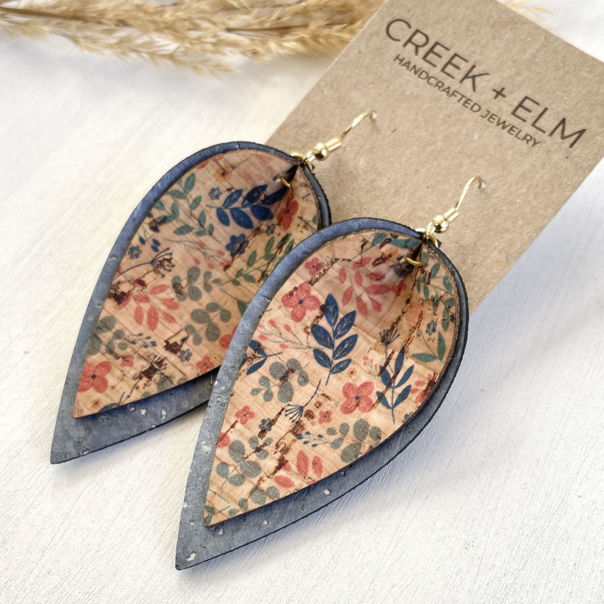 Floral patterned earrings with cork backing on a Creek &amp; Elm branded card.