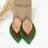 A pair of handmade dangle earrings displayed on a brown kraft card labeled 'CREEK + ELM HANDCRAFTED JEWELRY.' The earrings have silver fishhook wires and layered teardrop-shaped pieces: a light natural wood center, a medium brown textured middle layer, and a dark green speckled outer layer.