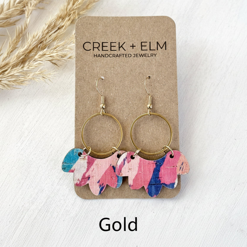 Pair of hoop earrings with colorful leaf-shaped charms on a Creek + Elm branded card.