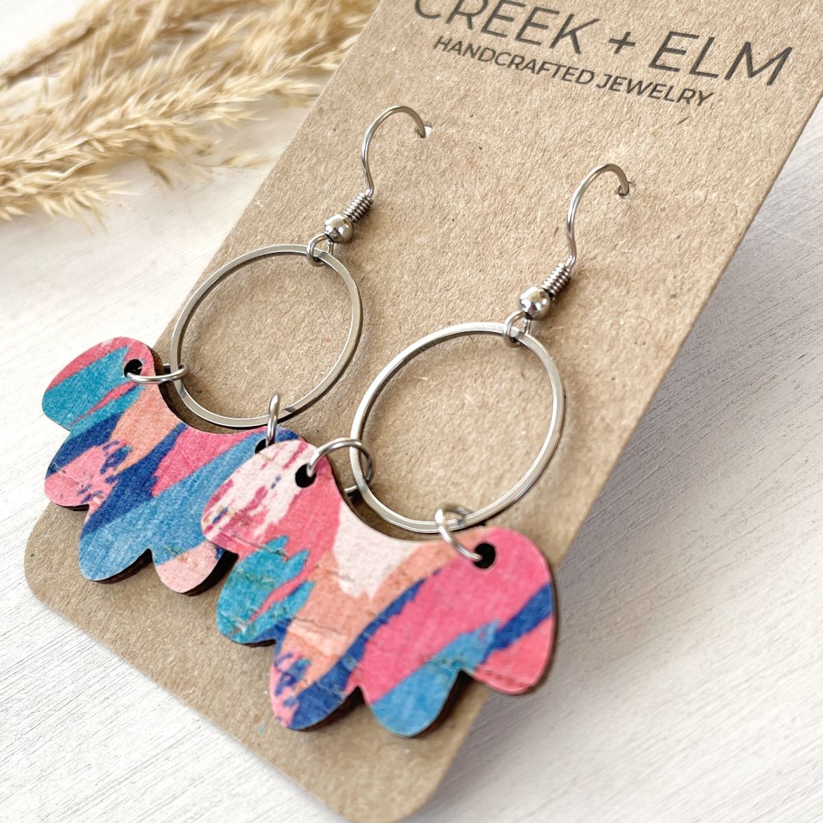 Earrings with colorful leaf-shaped pendants on a Creek + Elm branded card.