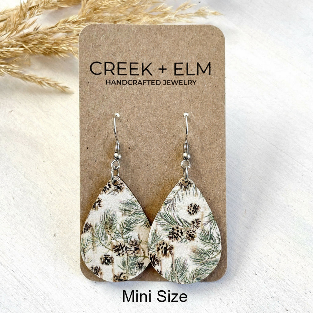 Teardrop-shaped earrings with nature-themed design on a 'Creek + Elm' branded card.