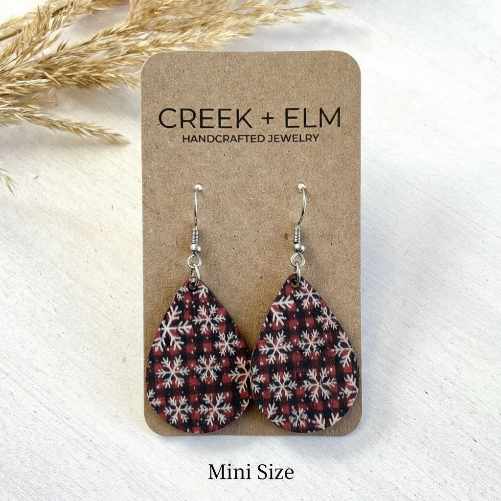 Pair of plaid patterned earrings on a Creek + Elm branded card with dried grasses in the background.
