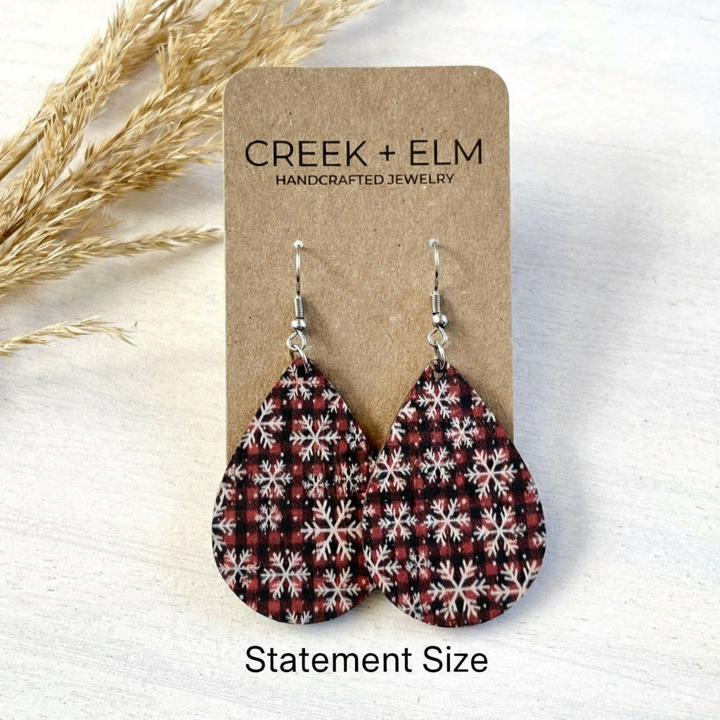 Teardrop-shaped earrings with a snowflake pattern on a Creek + Elm branded card.